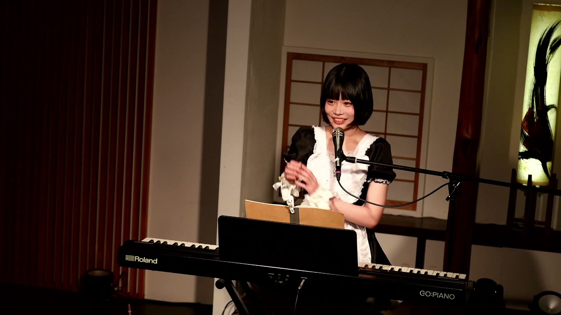中村菫（黒と白のワンピース姿で鍵盤の前に座り笑顔を見せる）